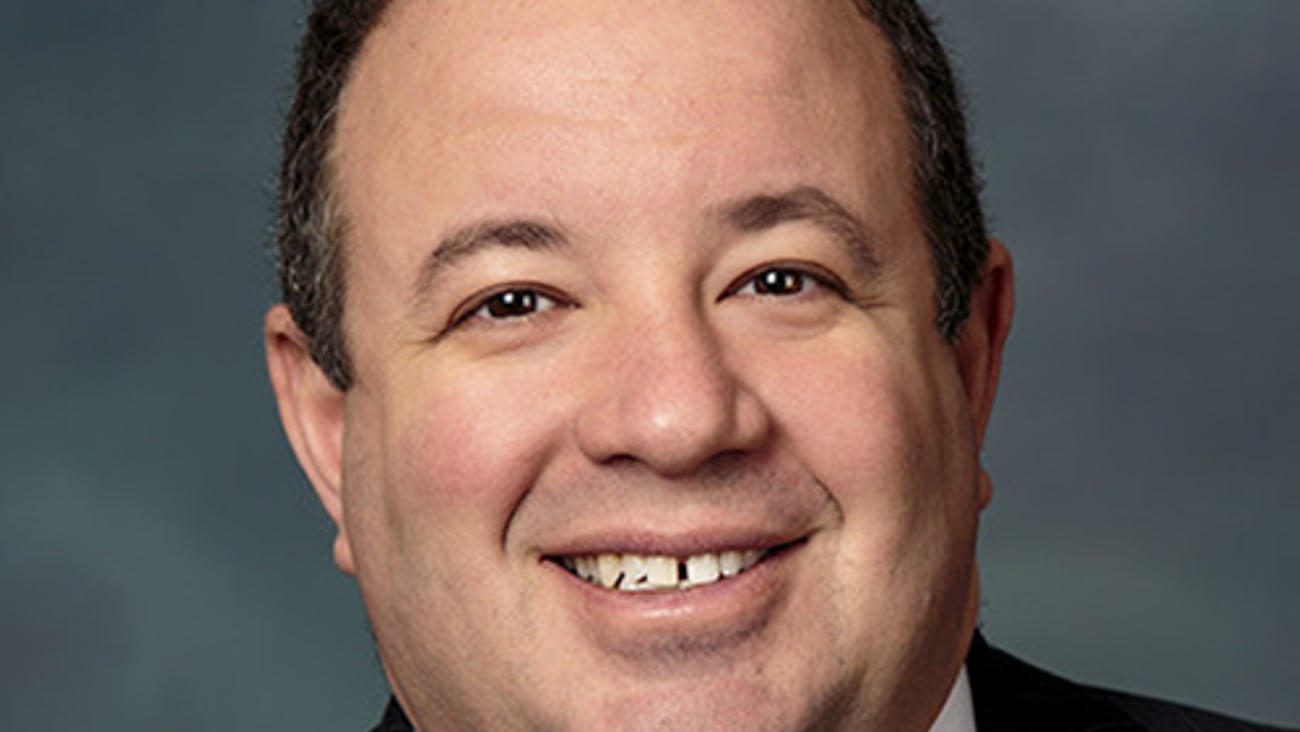 a man wearing a suit and tie smiling at the camera