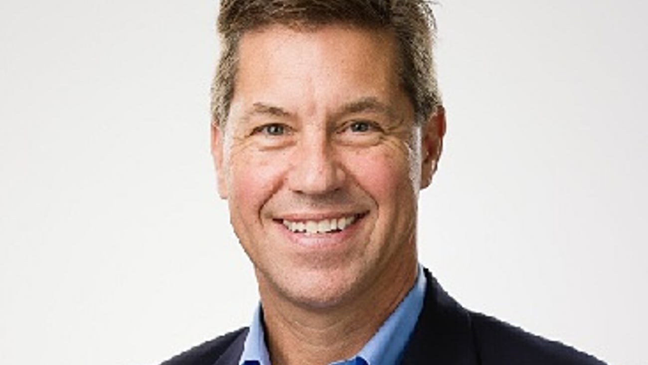 a man wearing a suit and tie smiling at the camera