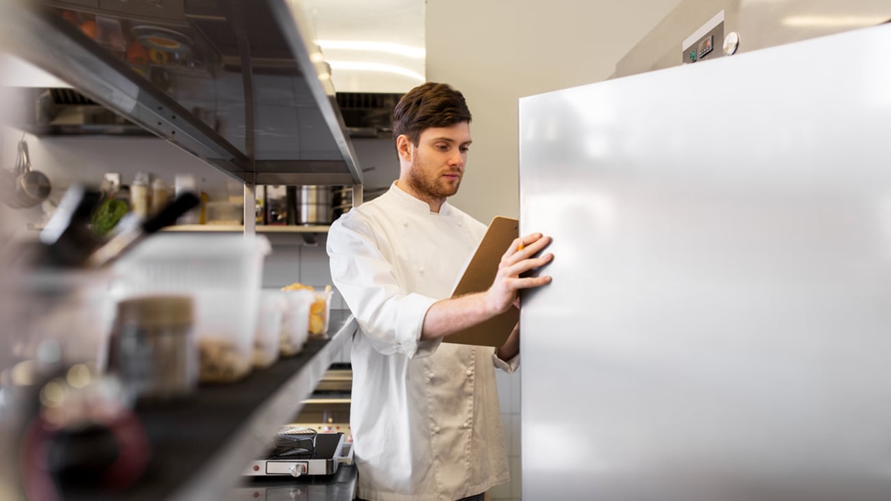 a person standing in front of a refrigerator with inventory checklist