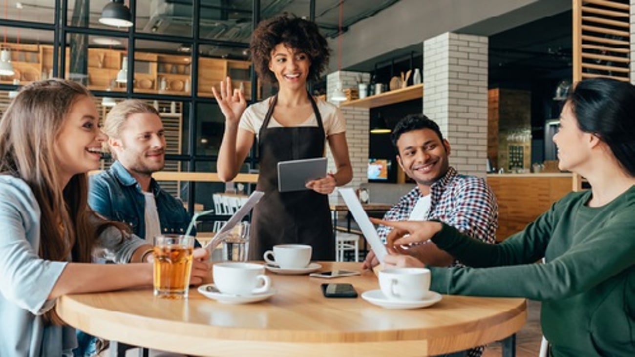 server with tablet and happy diners