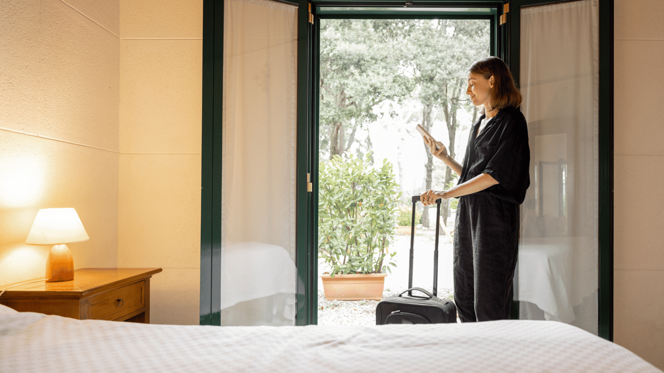 woman standing in hotel room using phone to check out