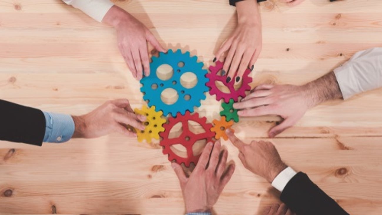 colored cogs hands on a table