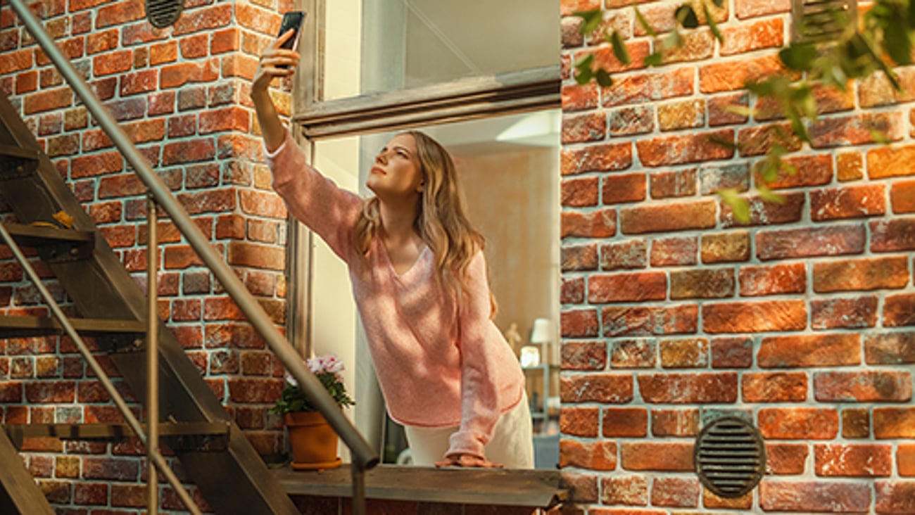 woman leaning out window searching for cellular signal