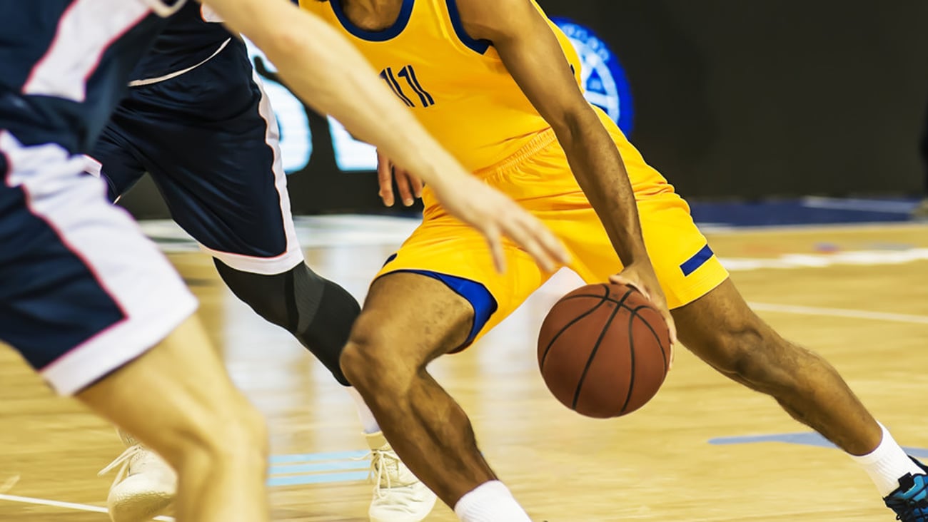 The basketball ball is on the basketball player's hand; Shutterstock ID 1475786261