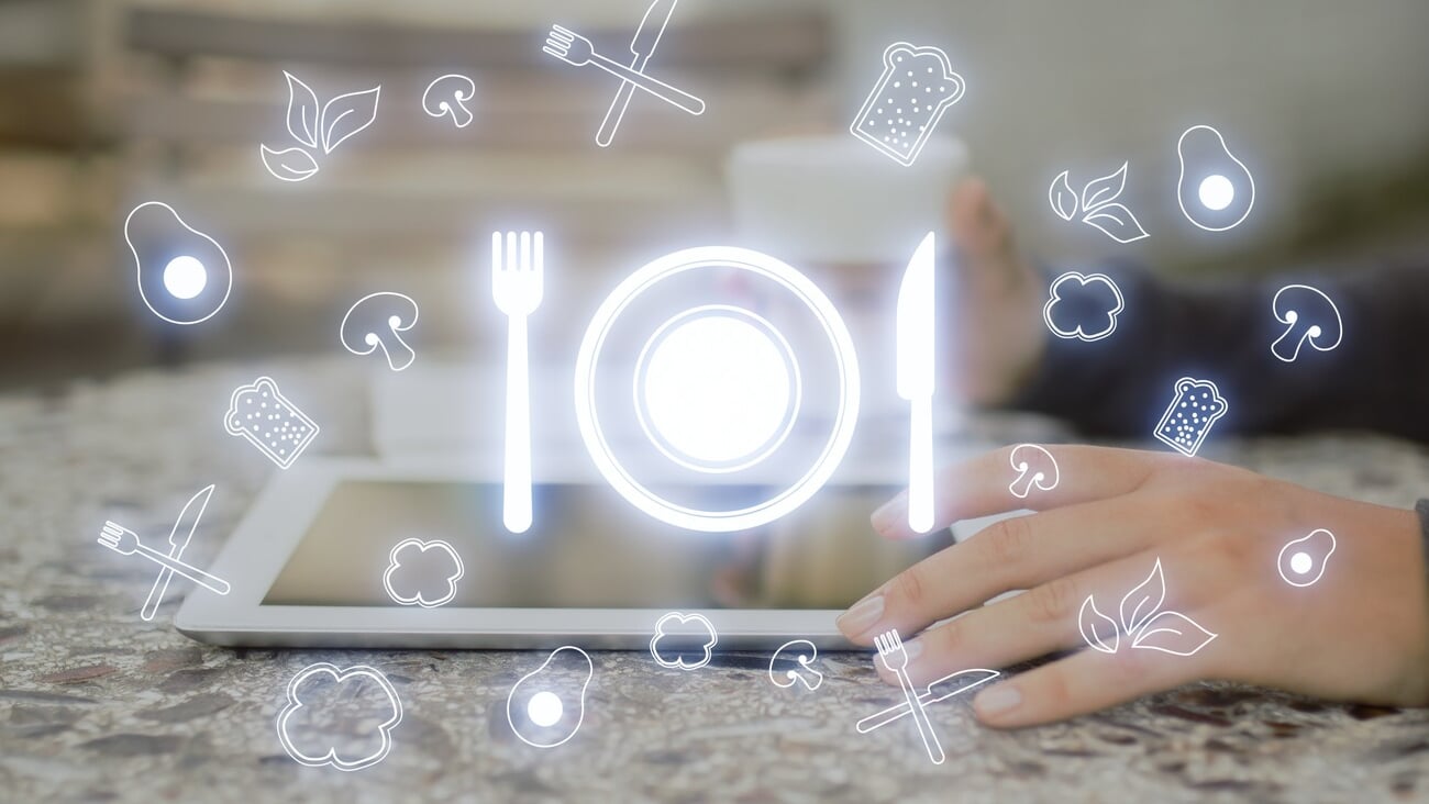 Futuristic restaurant menu application concept with glowing silverware hologram on blurry background. Side view of female hands using tablet at desktop on blurry background. Double exposure; Shutterstock ID 2268778489