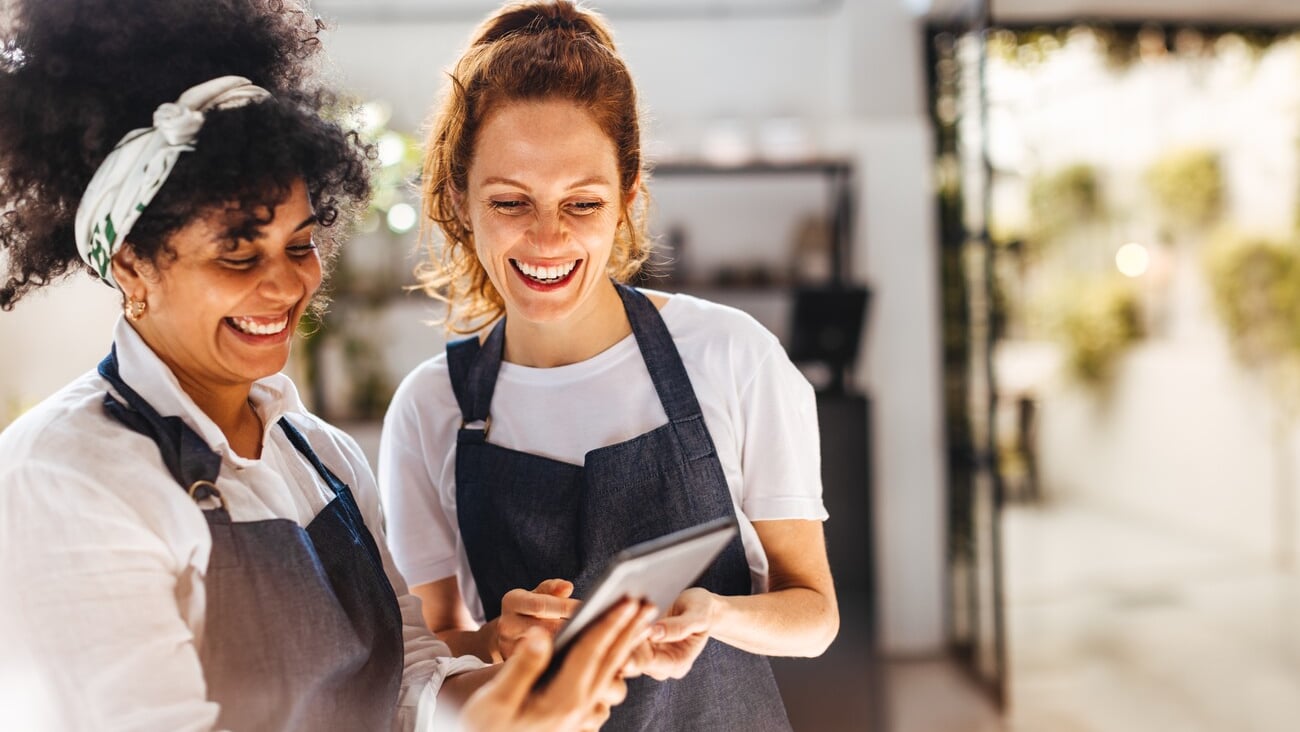 Happy female employees using a mobile app on a tablet to manage the daily operations of their restaurant. Women working together to ensure that customers receive the best hospitality service.; Shutterstock ID 2363837863