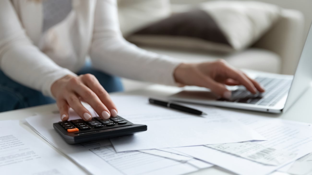 Close up of woman busy paying bills online on computer calculating household finances or taxes on machine, female manage home family expenditures, using calculator, make payment on laptop; Shutterstock ID 1716917581