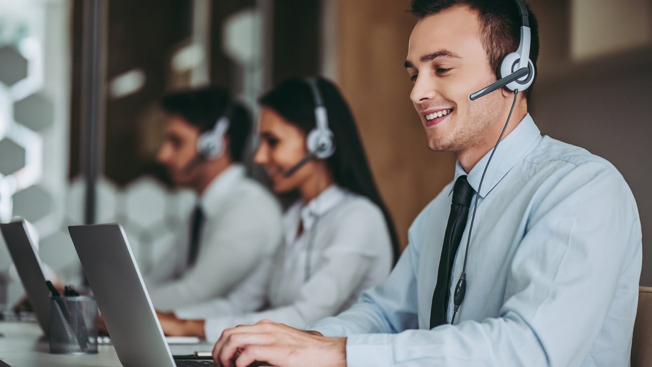 How can I help you? Beautiful call center workers in headphones are working at modern office.; Shutterstock ID 726010987