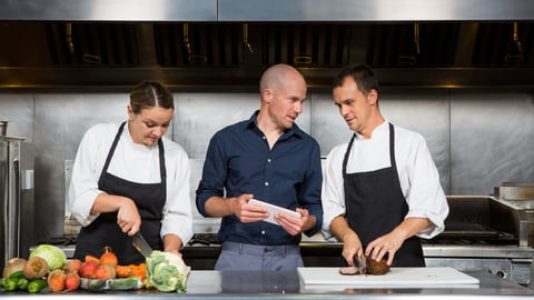 a group of people standing in a kitchen preparing food