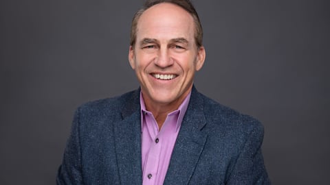 a man wearing a suit and tie smiling at the camera