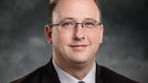 a man wearing a suit and tie smiling at the camera