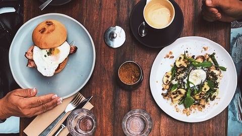 a person holding a plate of food on a wooden table