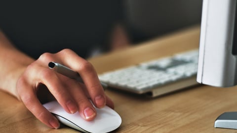 a person sitting at a desk using a computer mouse