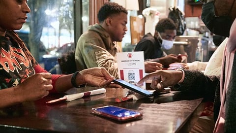 a group of people sitting at a table eating ramen using Toast