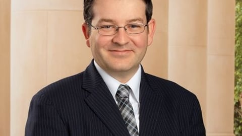 a man wearing a suit and tie smiling at the camera