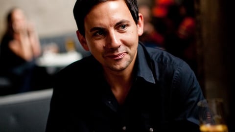 a man sitting at a table with wine glasses