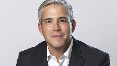 a man wearing a suit and tie smiling at the camera