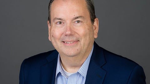 a man wearing a suit and tie smiling at the camera