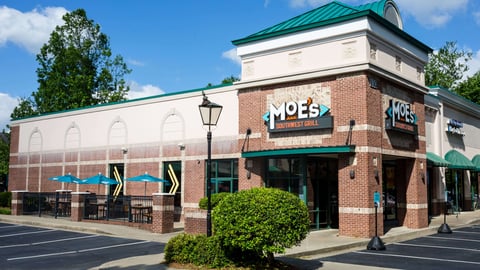 a large brick building with a clock on the side of a road