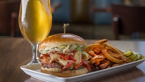 a plate of food and a glass of beer on a table from Bru Burger Indy