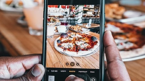 a hand holding a piece of pizza