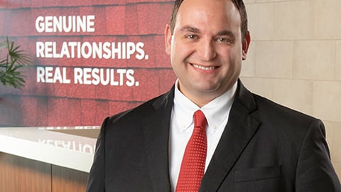 a man wearing a suit and tie smiling at the camera