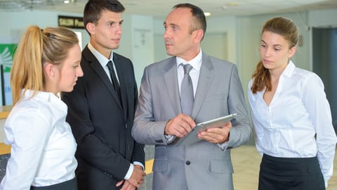 a group of people standing next to a person in a suit and tie