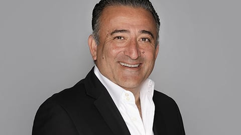 Arash Azarbarzin wearing a suit and tie smiling at the camera