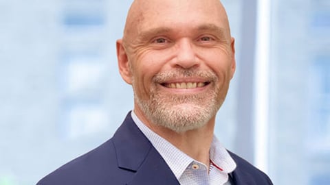 a man wearing a suit and tie smiling at the camera