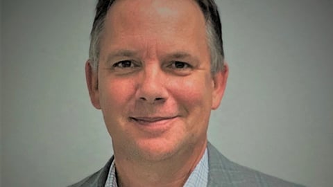 a man wearing a suit and tie smiling at the camera