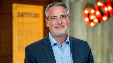 a man wearing a suit and tie smiling at the camera