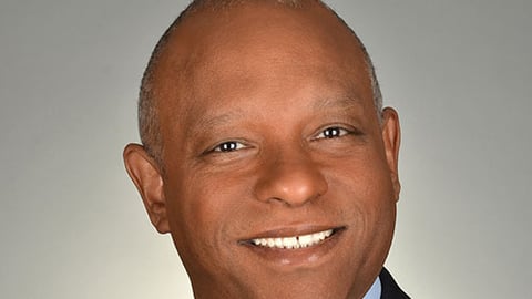 a man wearing a suit and tie smiling at the camera