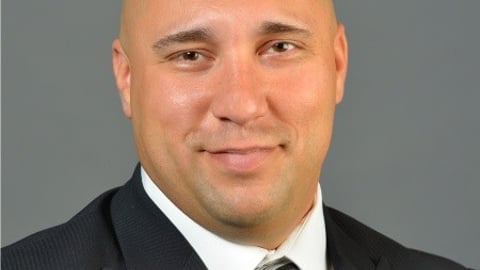 a man wearing a suit and tie smiling at the camera