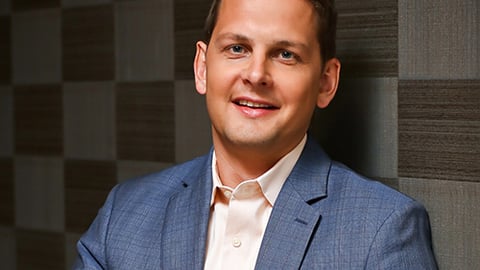 a man wearing a suit and tie smiling at the camera