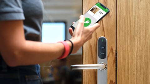 a hand holding a remote control on a wooden surface