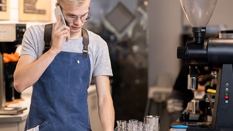 person,building,table,man,standing,cellphone,phone,talking,using,woman,front,sitting,food,holding,glasses,laptop,computer,young,kitchen,street