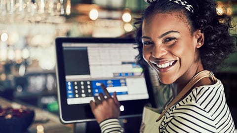 a woman sitting at a table with a laptop and smiling at the camera