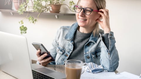 a person sitting at a table using a laptop while talking on the phone