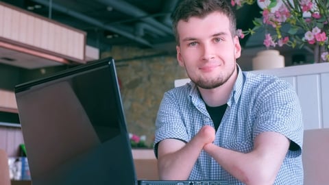 young man with amputated arms in front of computer