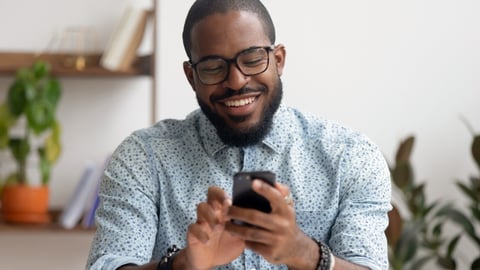 man smiling while looking at his cell phone