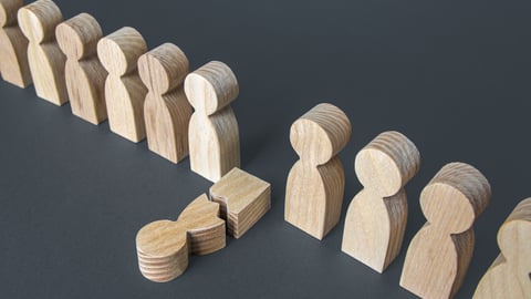 broken wooden person in a line of wooden people