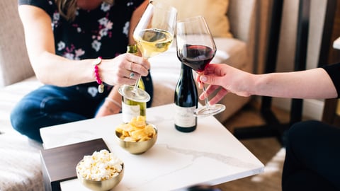 Two women clinking wine glasses