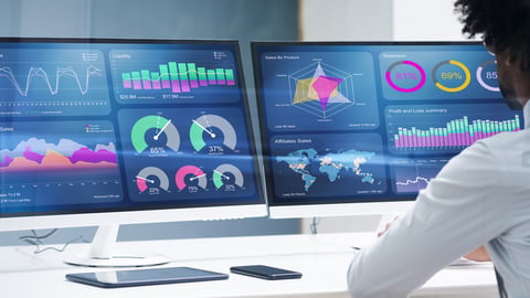 Man in front of computer screens using predictive analytics software