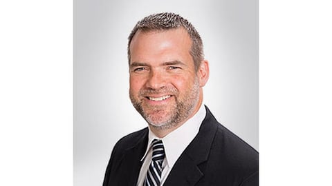 a man wearing a suit and tie smiling at the camera