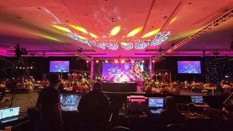 a group of people sitting on stage with stage lights and an audience