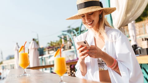 Smiling woman using phone at outdoor bar