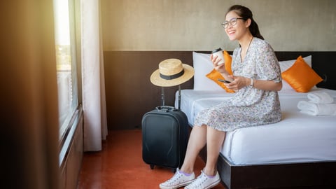 woman sitting on hotel bed, smiling