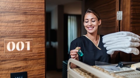 a housekeeper brining towels into a hotel room