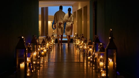 a couple at the end of a dark hallway illuminated by romantic candlelight