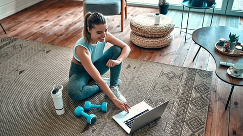 woman getting ready to exercise while watching her laptop